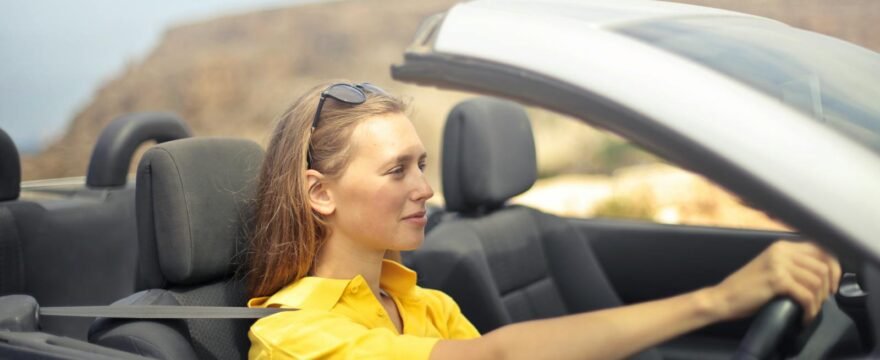 A young woman enjoys driving a convertible on a sunny day in Malta.