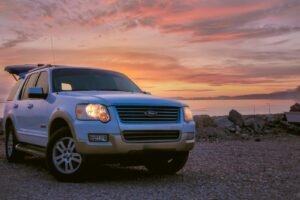 A white Ford Explorer SUV parked by the beach at sunset, offering a picturesque view in Dubai.